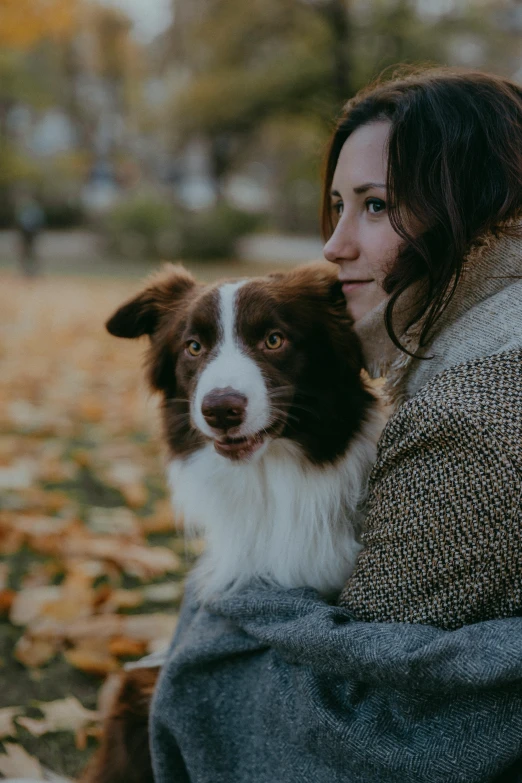 woman sitting on the ground holding dog in her lap