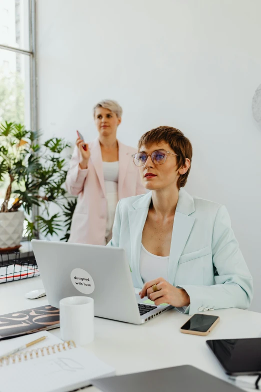 a woman sitting at a desk looking at her laptop