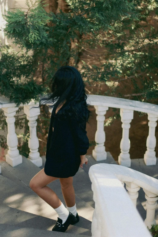 a young woman in black with white socks is posing on some stairs