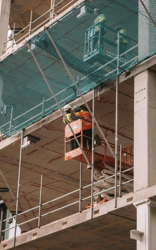 the construction worker on the lift is working to secure the net from falling