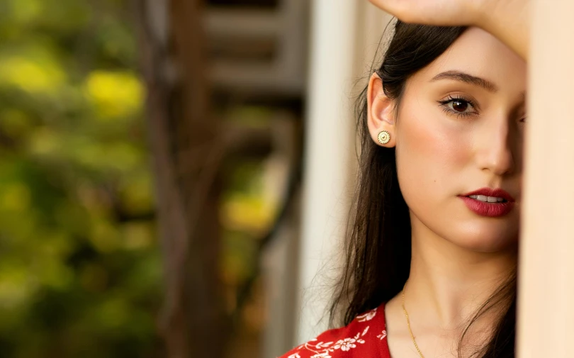 an asian woman poses for a po while wearing a red dress