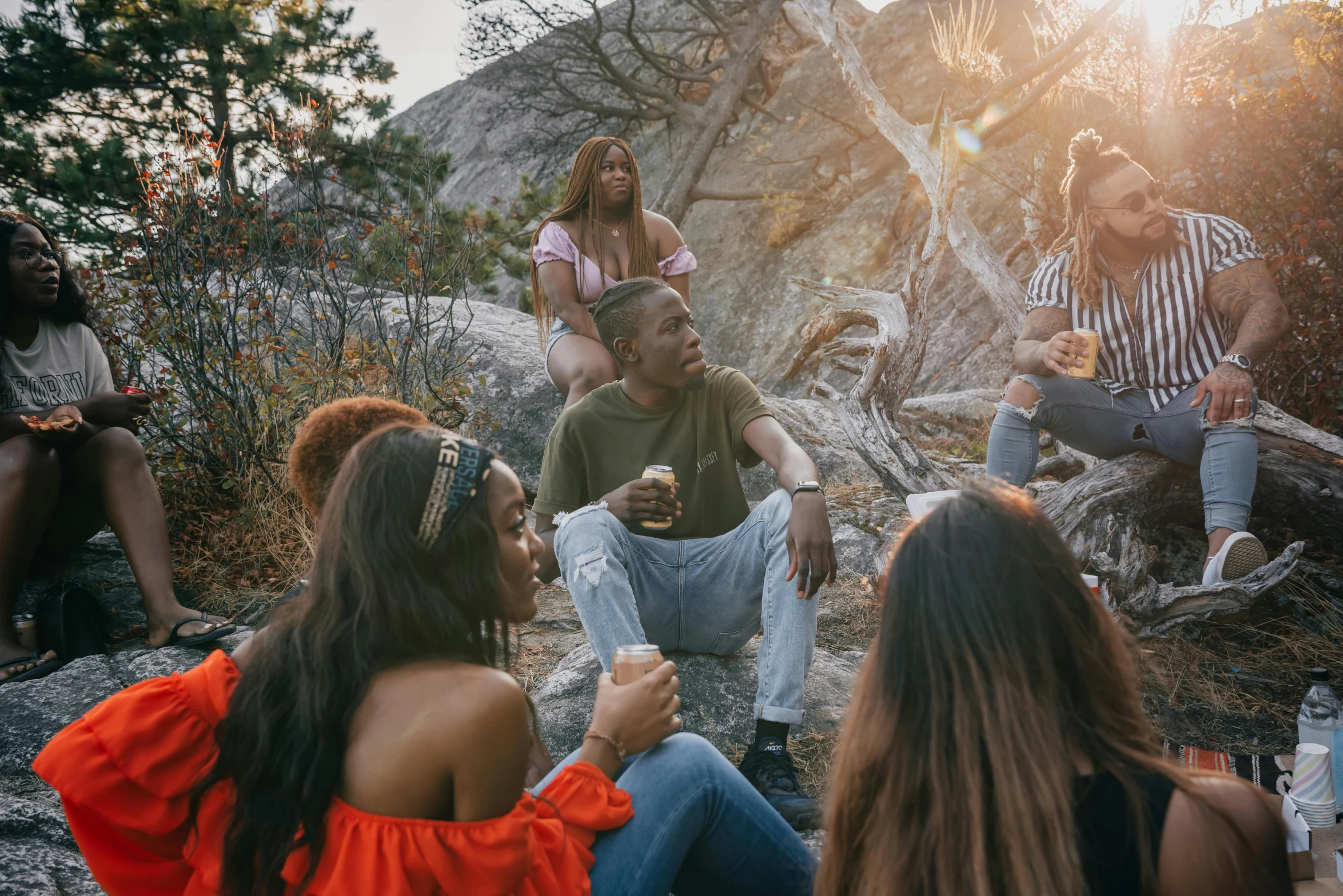 a group of people sitting and standing in the wilderness