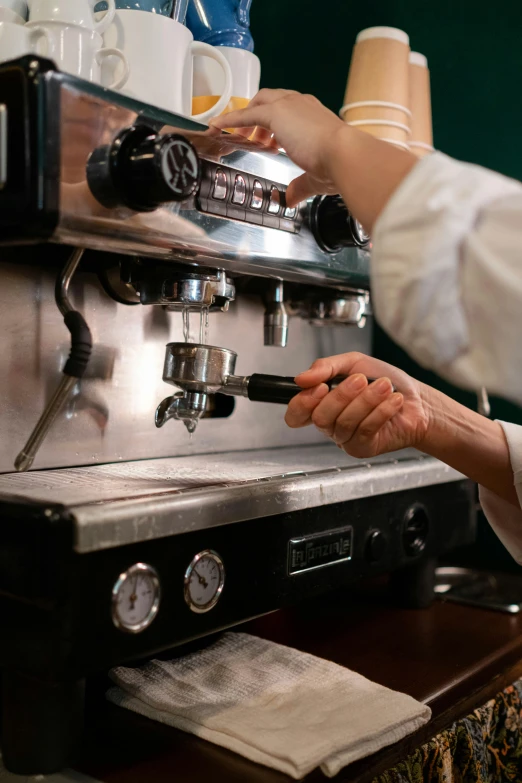 the person is filling up a cup of coffee with one hand