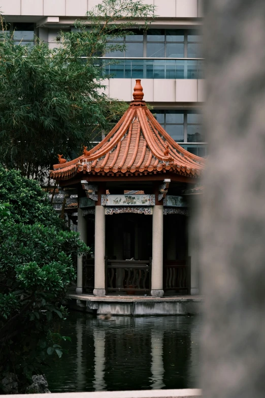 a small building with an asian roof next to water