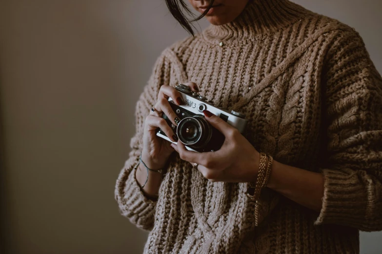 a woman wearing sweater and holding a camera