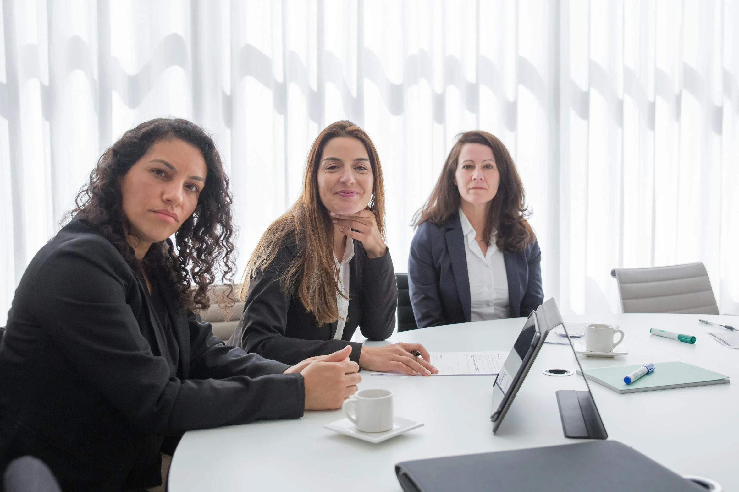 three women are sitting around a table with papers