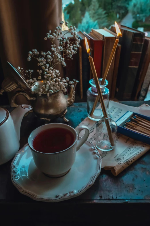 a table that has an open book, teacup, coffee pot and tea set on it