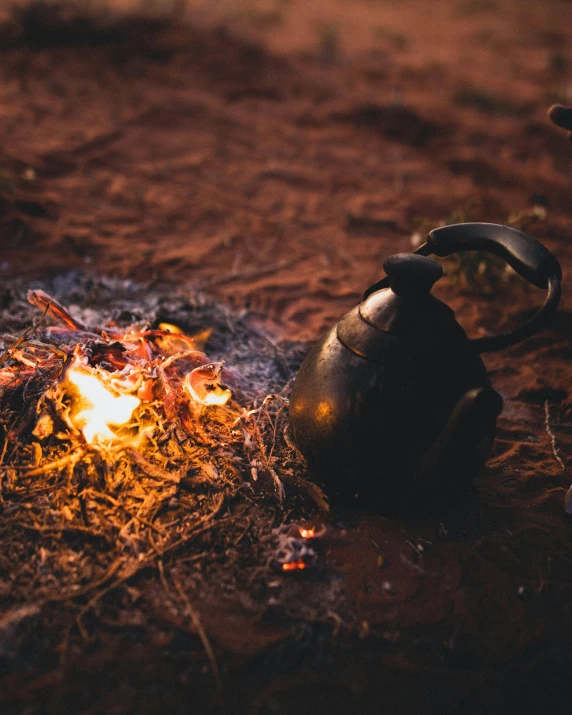 a kettle sitting on top of a fire in the grass