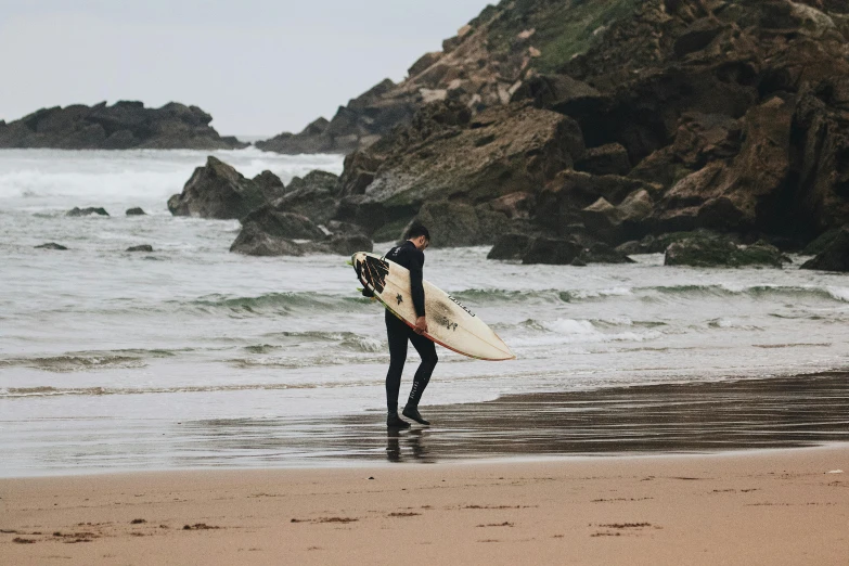 the man is carrying his surfboard out of the water