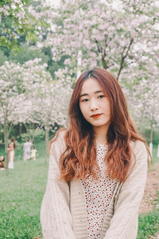 a woman standing in front of cherry trees wearing a white top