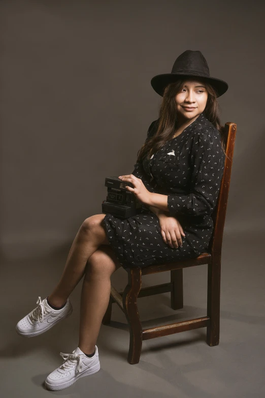 a woman sitting on a chair, wearing a hat
