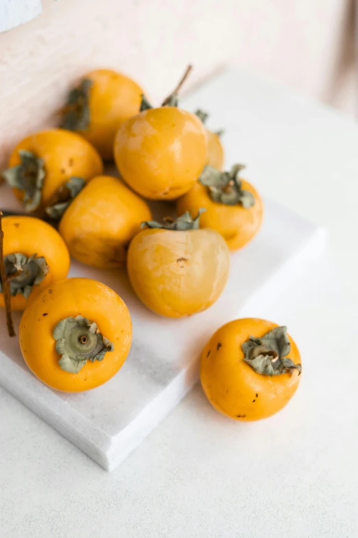 four yellow fruits sit on a white plate