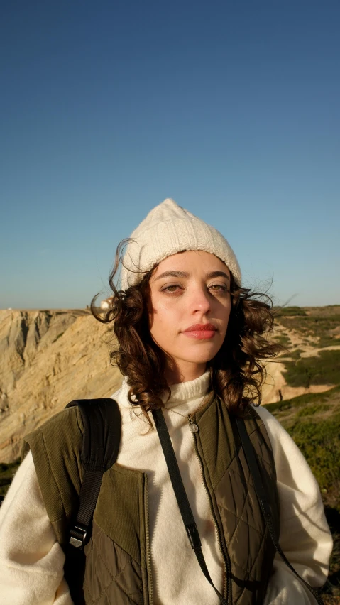 a woman with a hat stands near a mountain