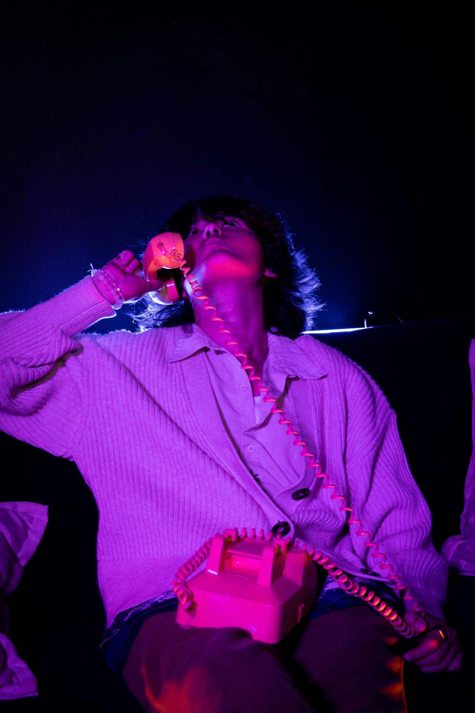 a woman in purple sitting on a chair while talking on a phone