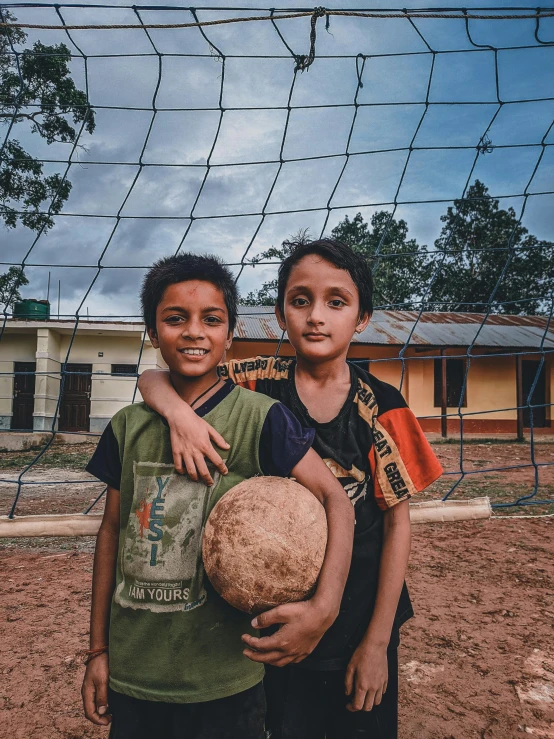 two s stand with their arms around a soccer ball