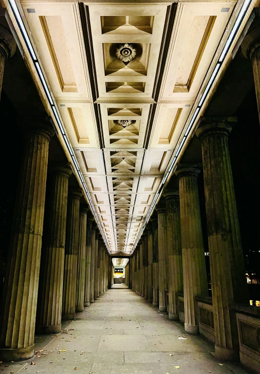 an empty walkway with columns and lights