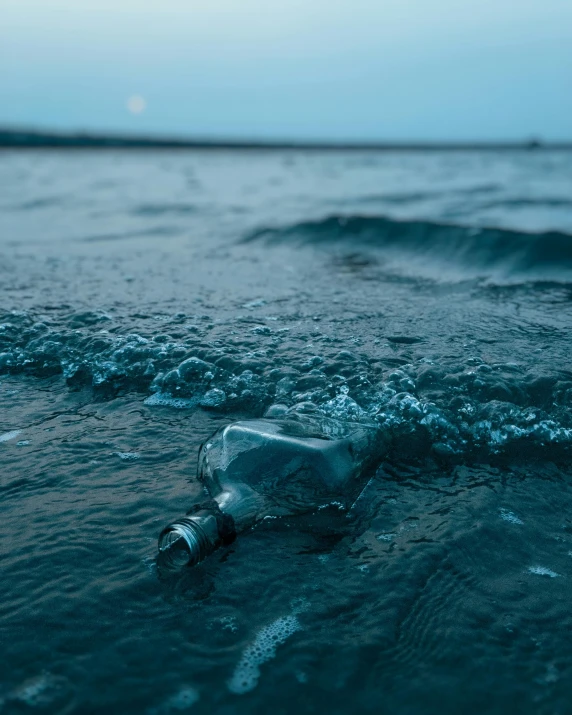a glass bottle partially submerged in the ocean