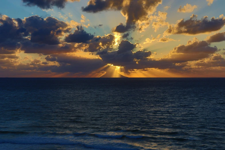 the sun's rays streak through the clouds and shine through the water