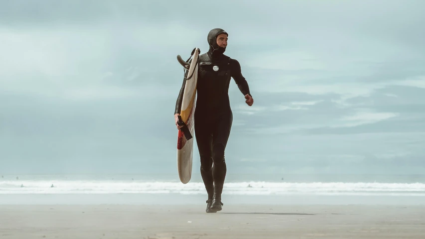 there is a woman walking along the beach holding a surfboard