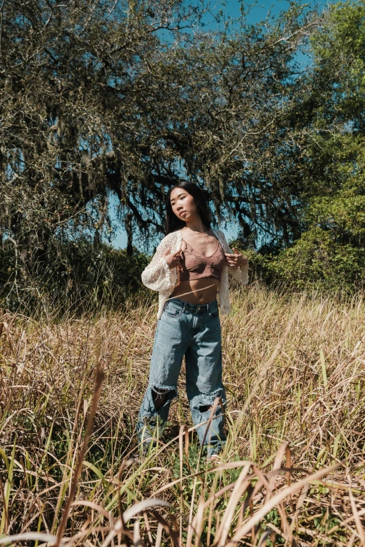 a woman standing in a field next to a tree