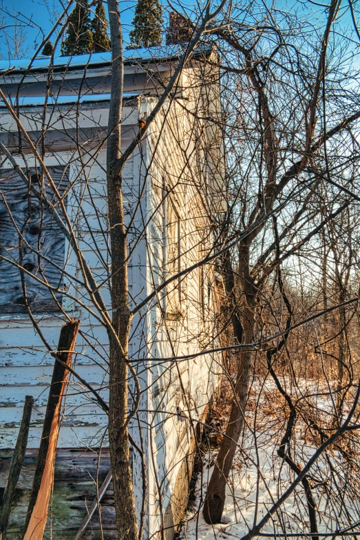 an old run down home is next to some trees