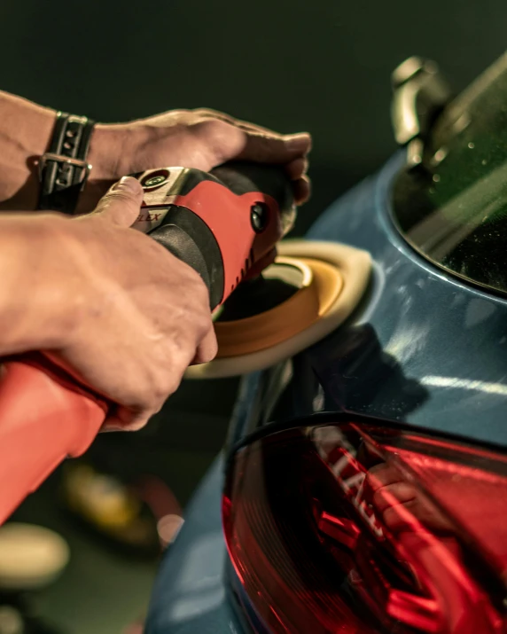 man is waxing the taillights of his car