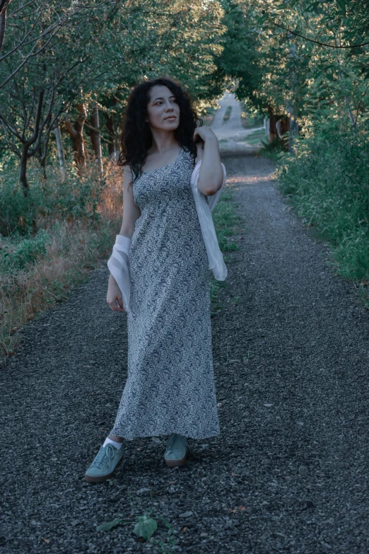 a woman in a dress holding an object by the side of a road