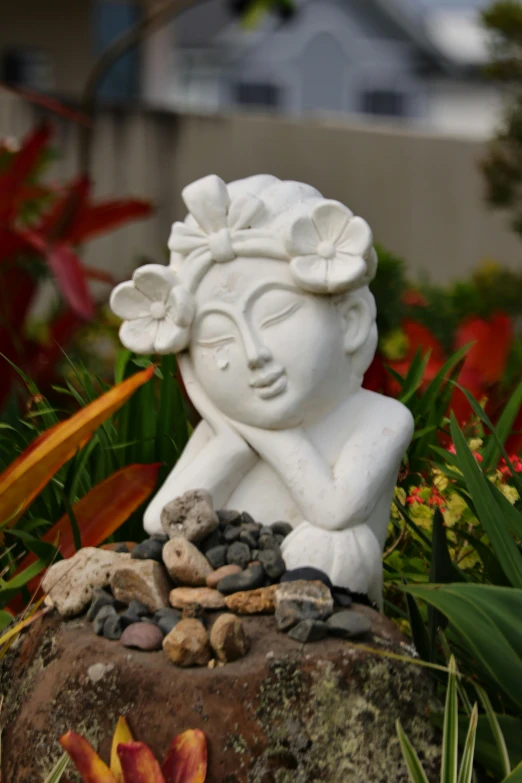 a small statue is sitting in some flowers