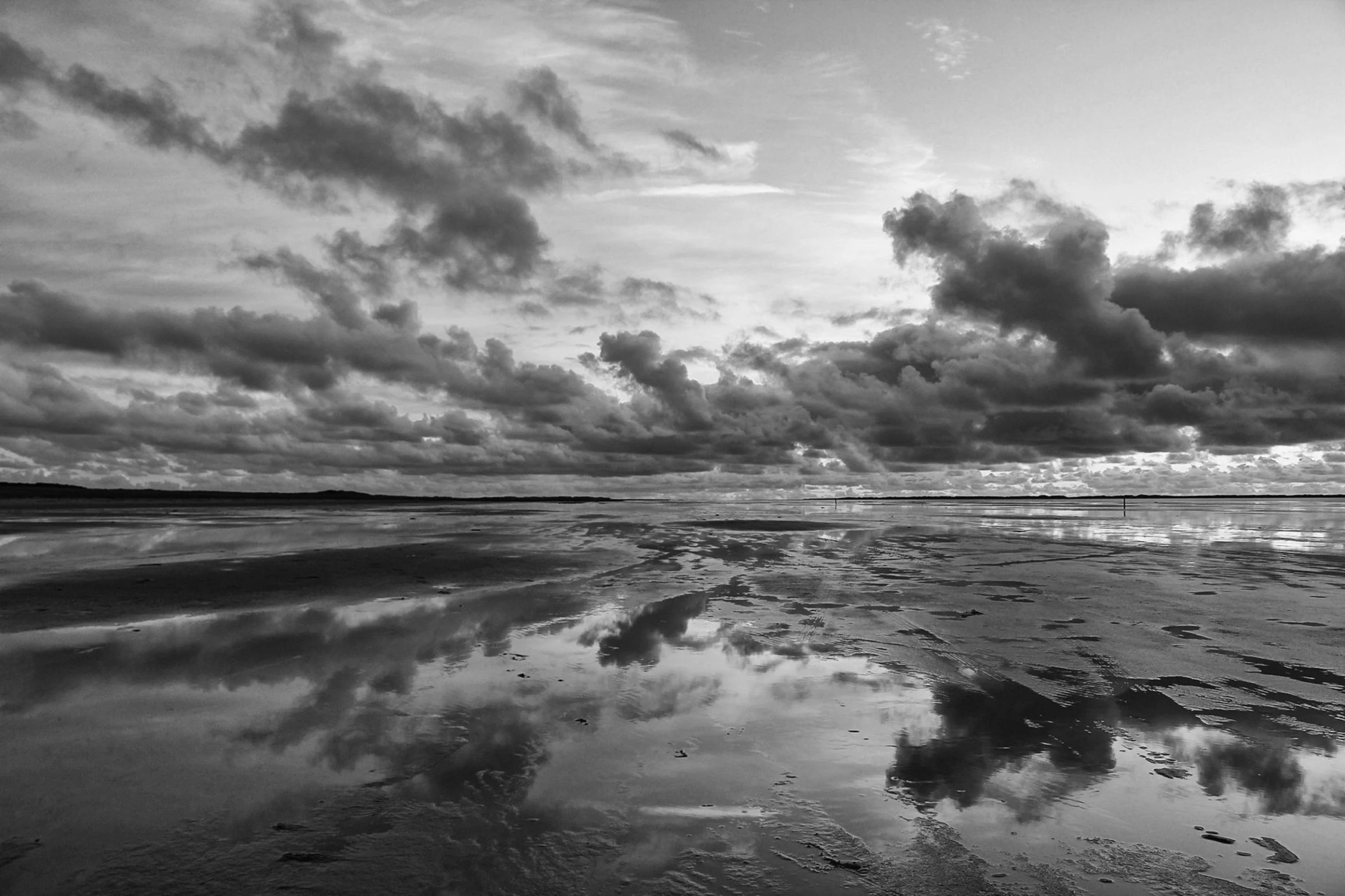 a beach with some very pretty clouds and water