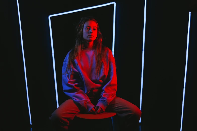 the woman is sitting on a chair in front of a black wall