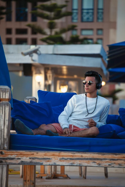 man on blue lounge chair with sunglasses on headphones