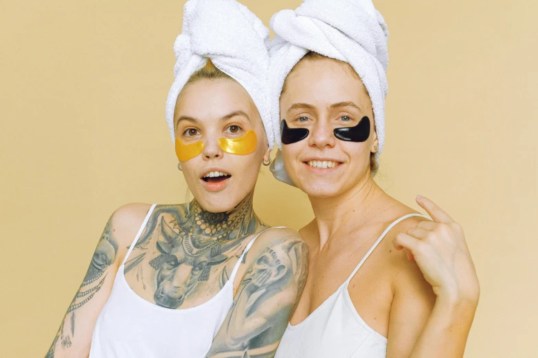 two women with face masks on pose for the camera