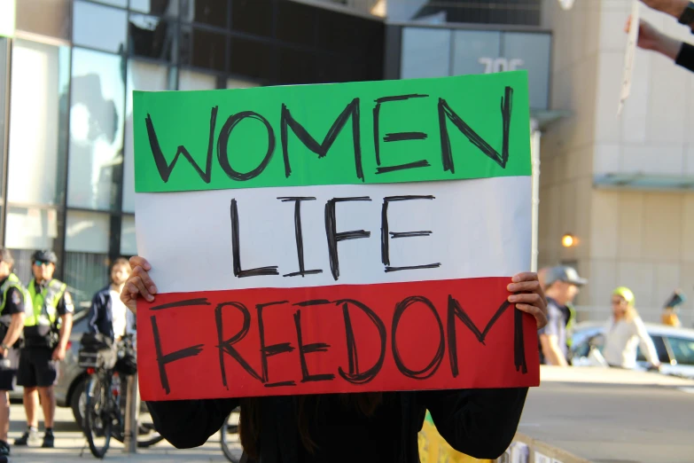 a person is holding a sign that says women life, freedom