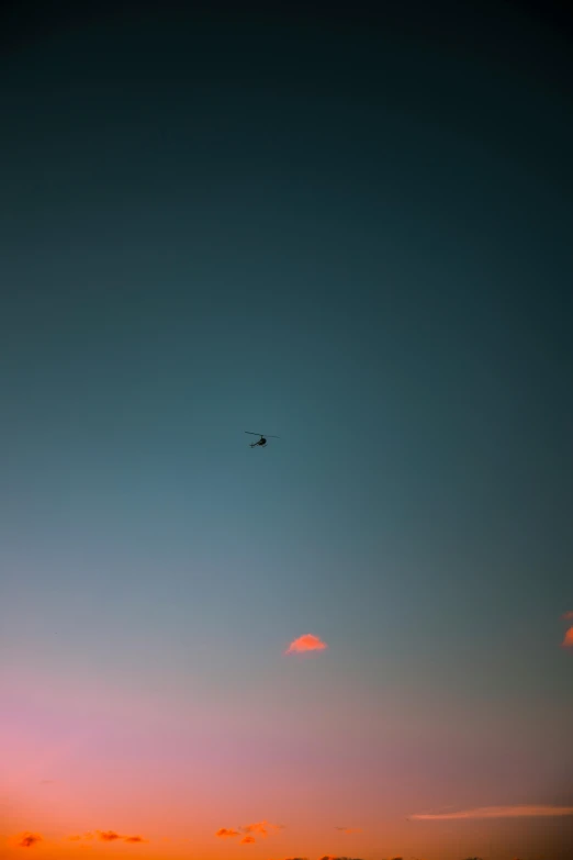 a sunset with a small plane flying in the sky