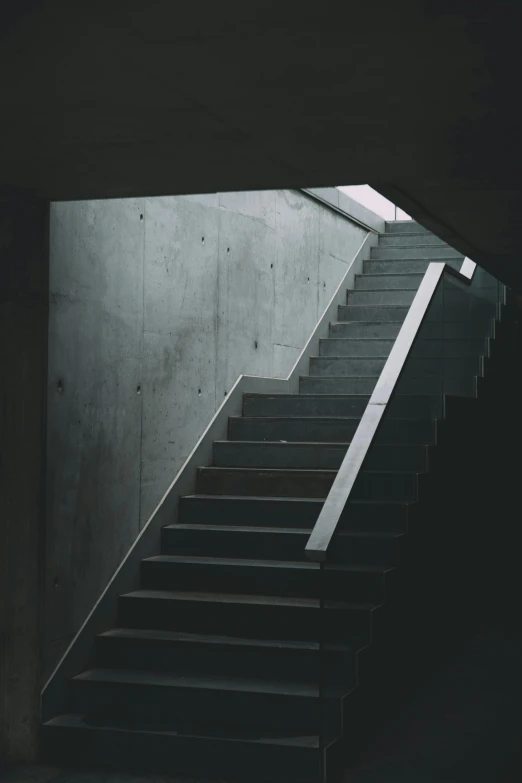 a stairway with a concrete wall and dark background