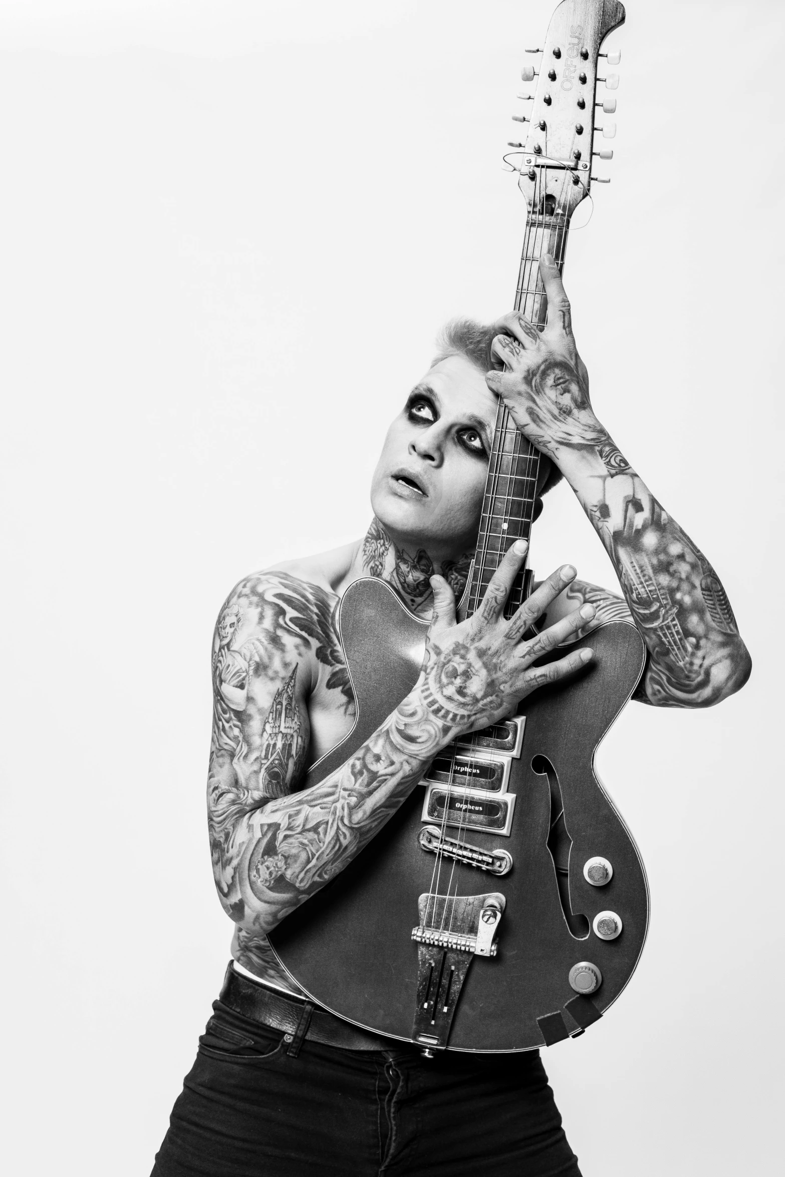 a man with tattoos and piercing holding a guitar