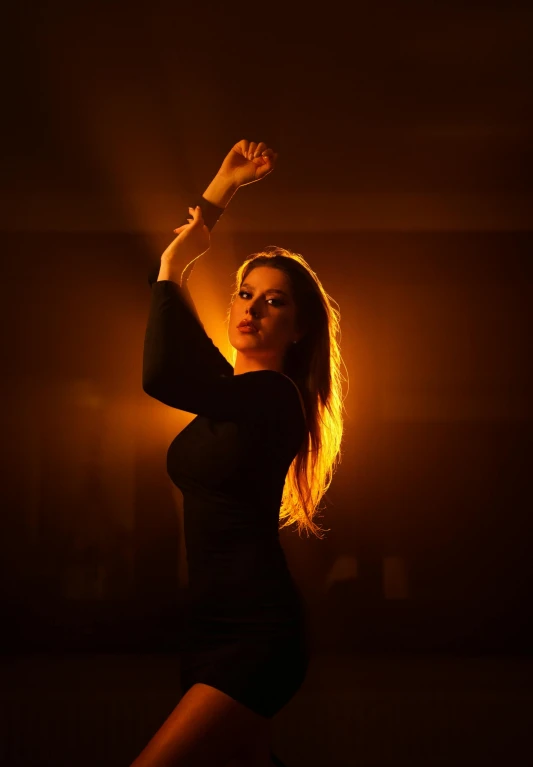 a woman in a dark room with her arms up