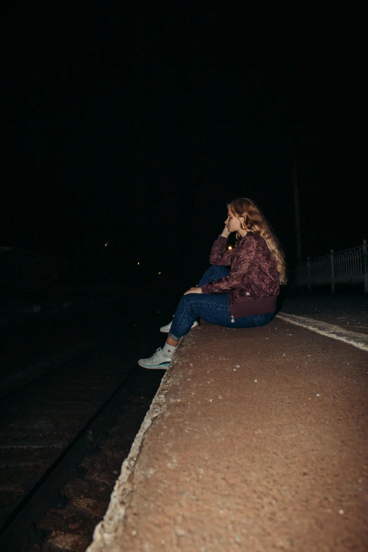 woman sitting on a walkway talking on her phone at night