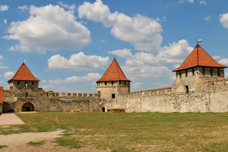 three towers against a stone wall with grass and stones