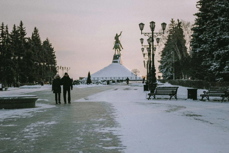 two people walking through a park in a city