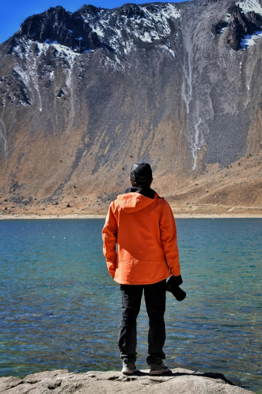 a person looking at the mountains from the shore