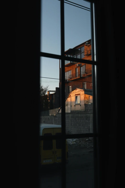 a yellow truck outside of a window with a light shining on it