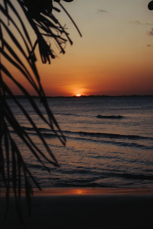 the sun is setting at a sandy beach