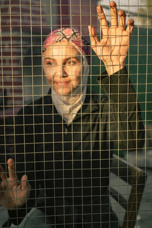 a woman standing behind a wire screen