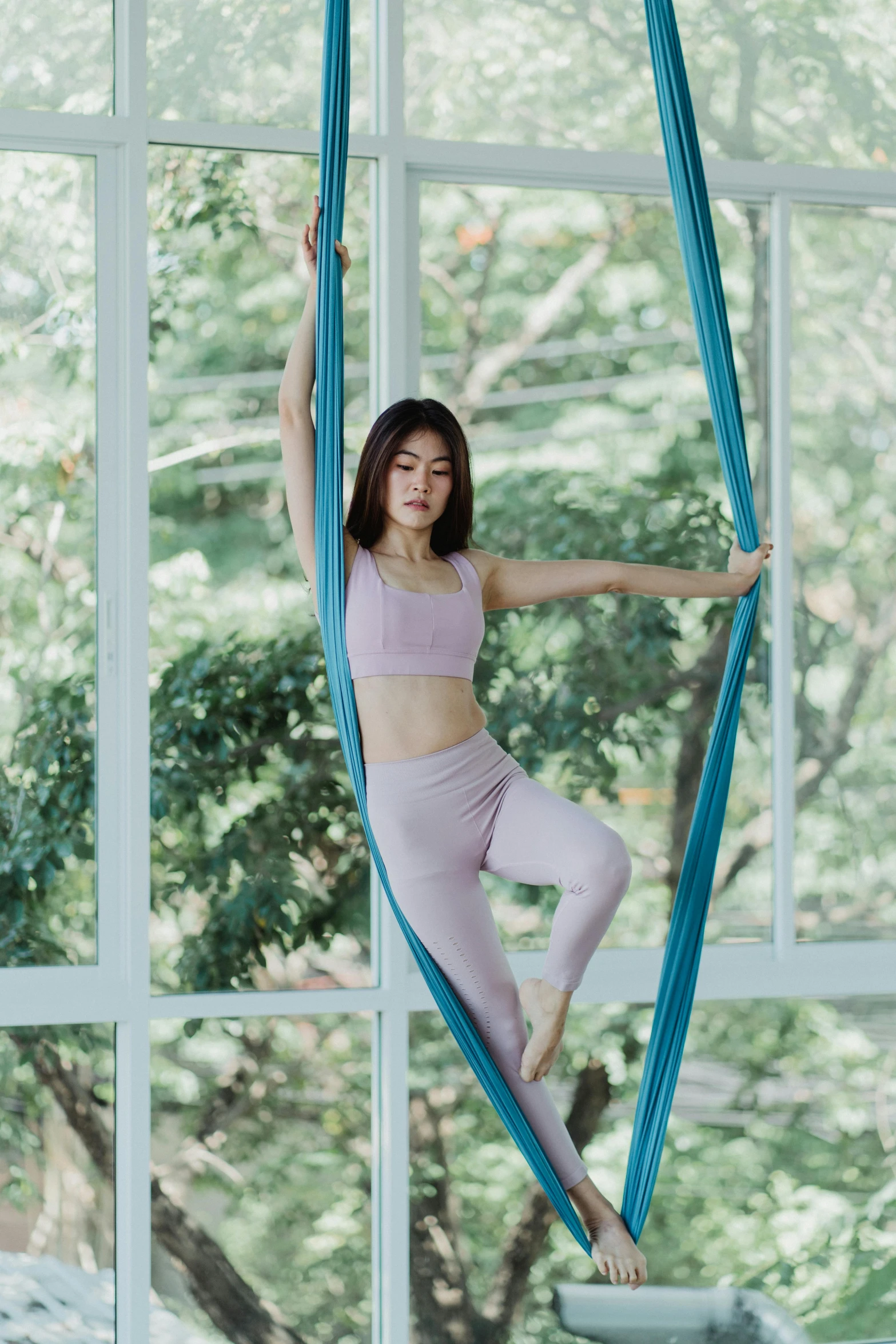 an attractive woman standing on a hammock, looking out the window