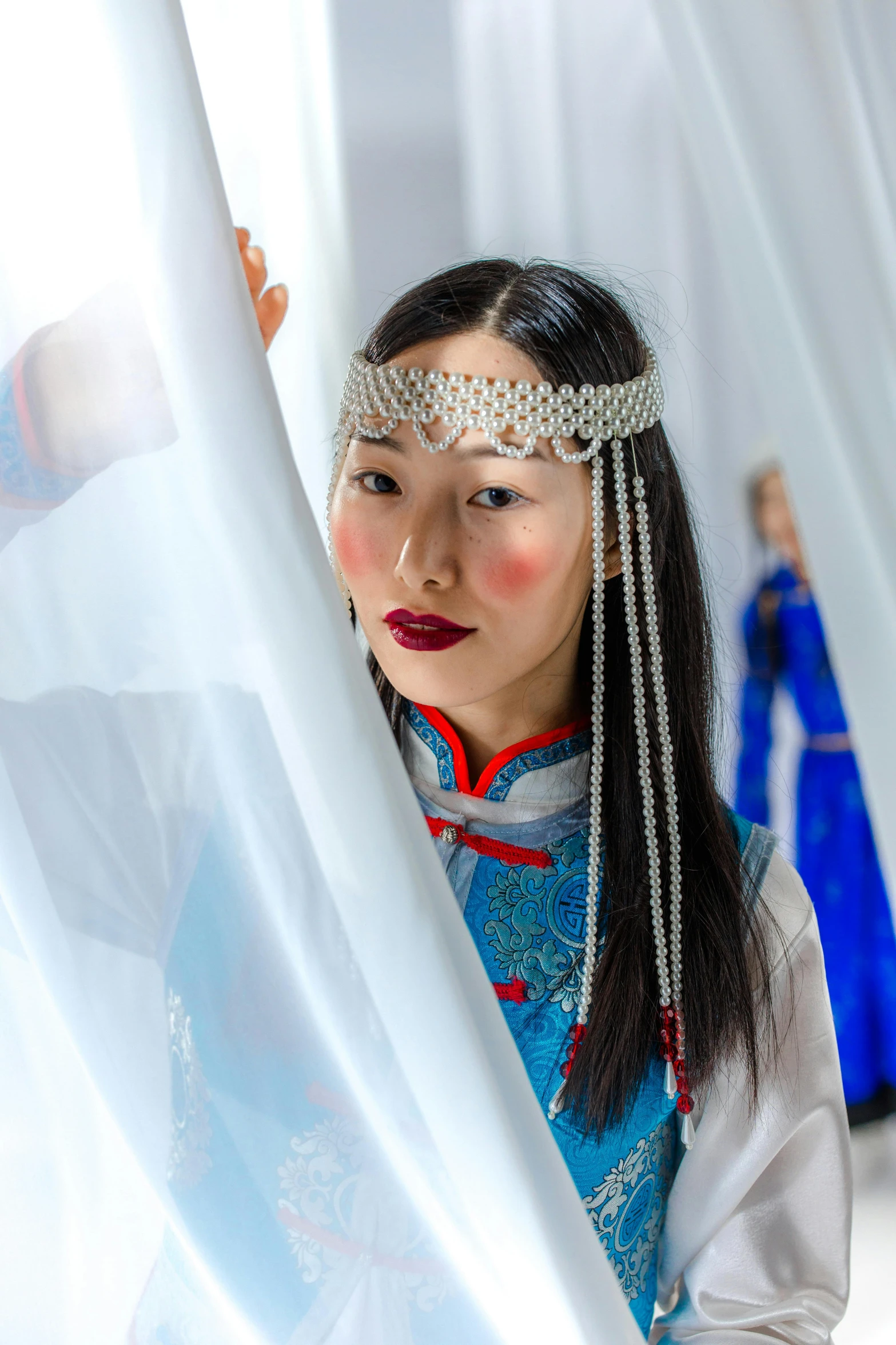 a woman in oriental garb holding a curtain behind her back