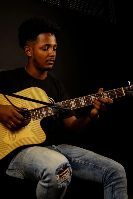 a man playing guitar sitting down next to a microphone