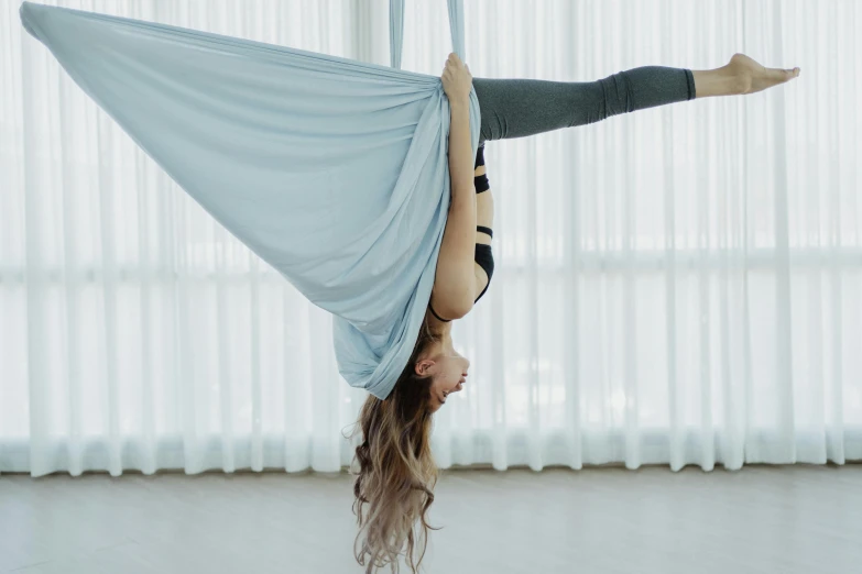 a woman is doing aerial aerial exercise with blue sheets