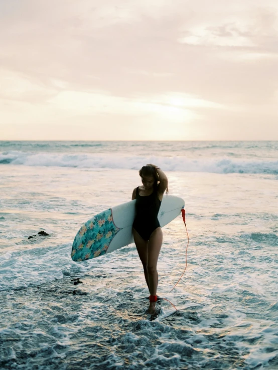 the girl is walking in water with her surfboard