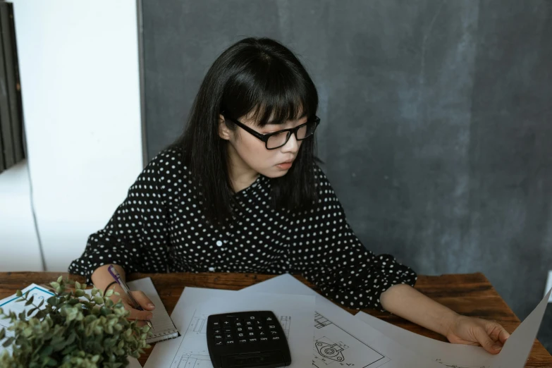 a woman sitting at a desk with papers and calculator